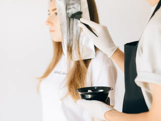 Colorista trabajando una sección de cabello con pincel y papel; fotografía de referencia.
