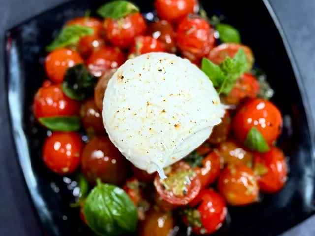Burrata con tomates cherry y albahaca en un plato.