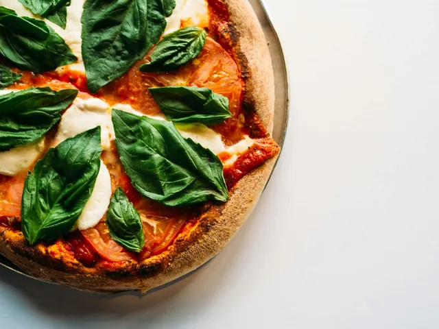 Pizza Margherita con mozzarella, tomate y hojas de albahaca.