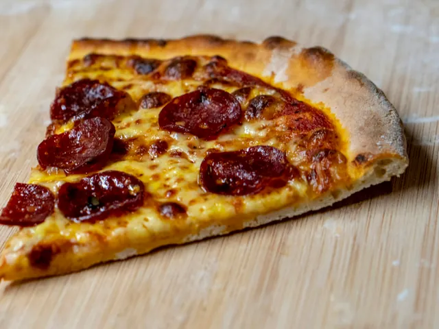 Porción de pizza con rodajas de pepperoni y mozzarella.