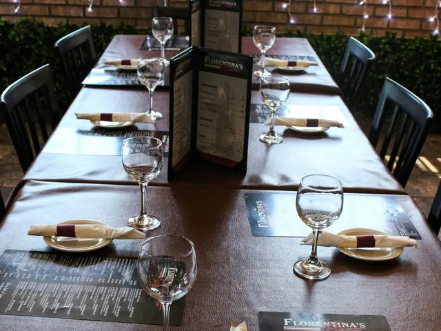 Mesa de restaurante preparada con platos, cubiertos y copas.